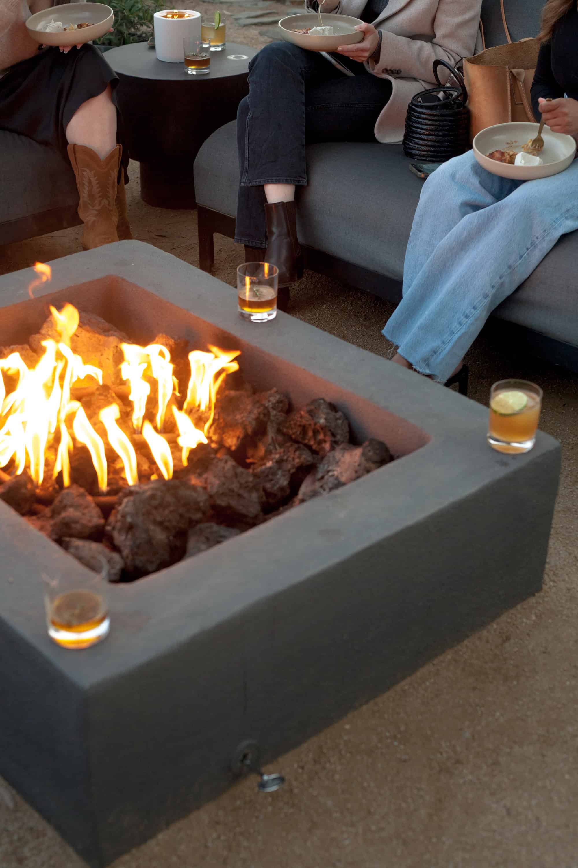 a fire pit with drinks in front of a person
