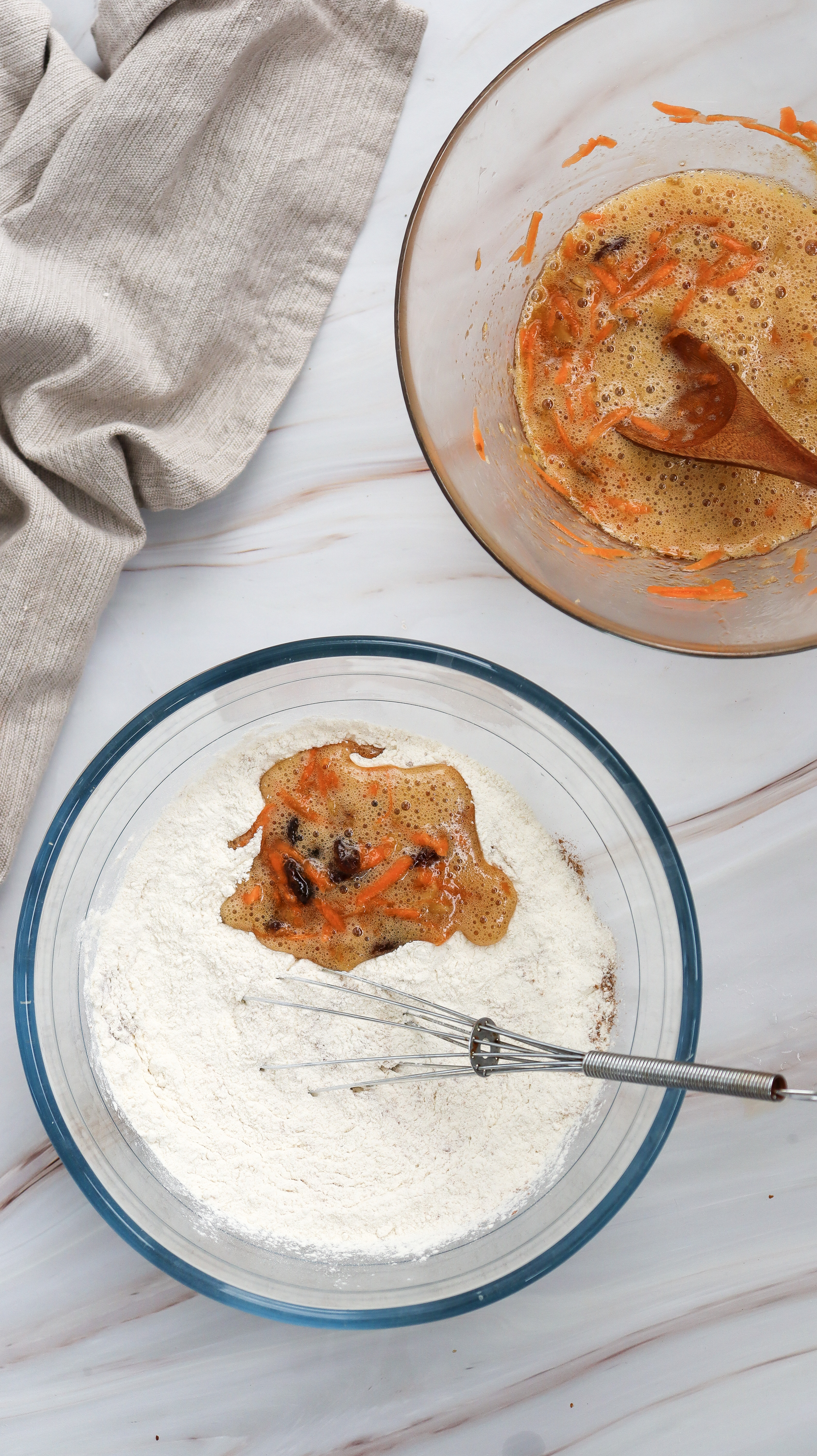A bowl of dry ingredients being mixed with wet ingredients for carrot cake muffins.