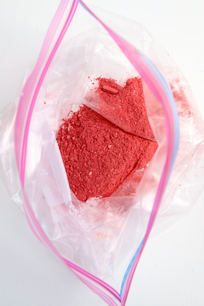 Blended freeze-dried strawberries and powdered sugar combined in a bag for Strawberry Puppy Chow.