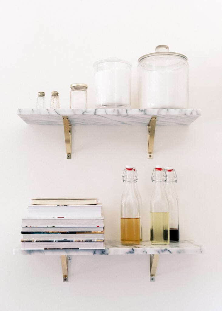 Party appetizer cookbook on a marble shelf with bottles of cooking oil and vinegars.