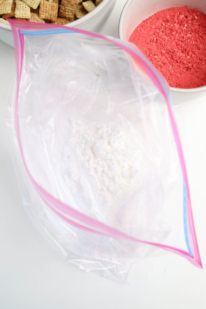A ziplock bag of powdered sugar, ready to coat Strawberry Puppy Chow.
