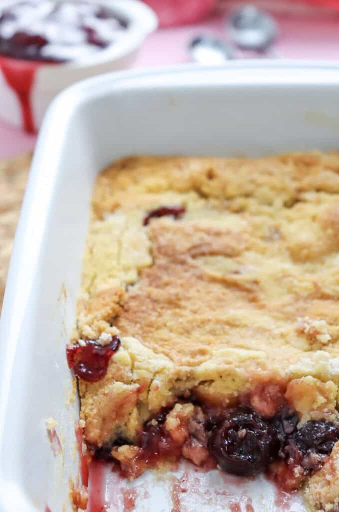 a baked Cherry Dump Cake in a white baking dish with golden brown topping and bubbly cherry filling.