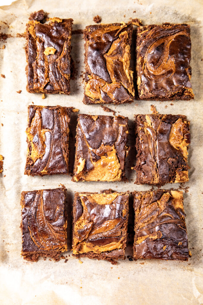 Slices of peanut butter swirl brownies stacked on parchment paper.
