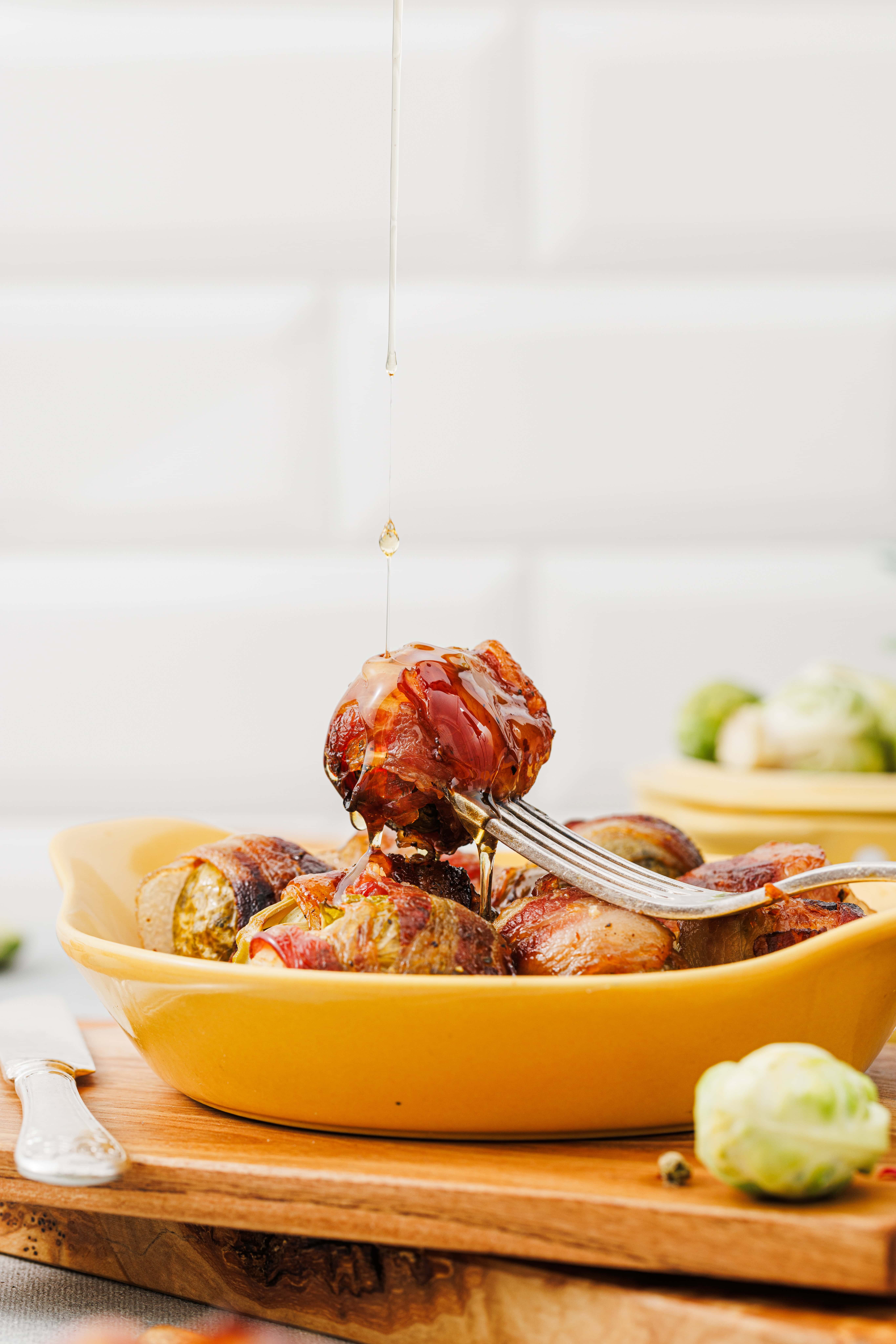 Crispy bacon wrapped brussel sprouts glazed with maple syrup on a serving platter.